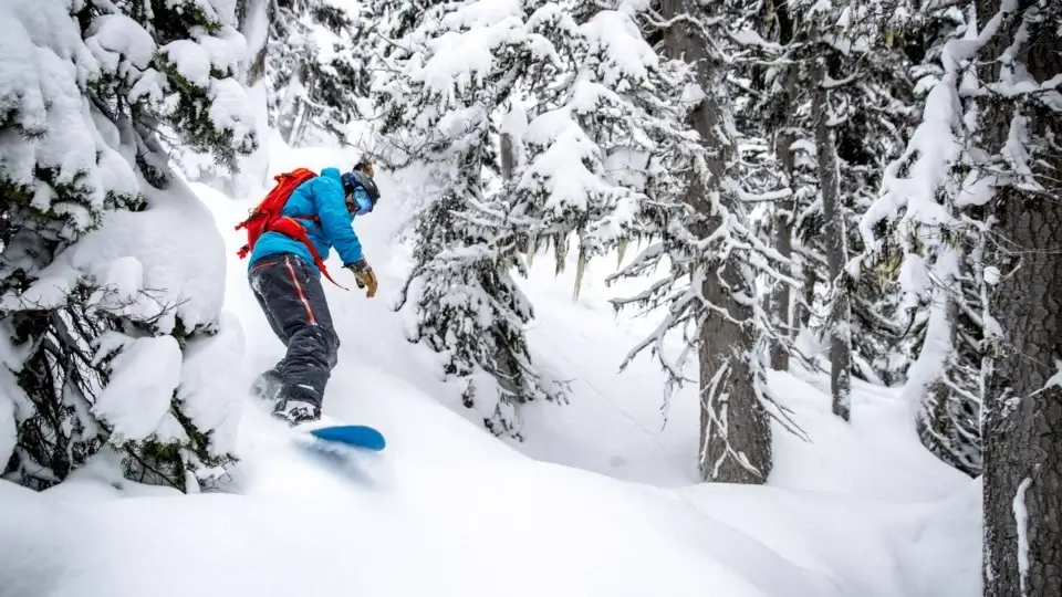 Snowboarder hiking up a snowy peak