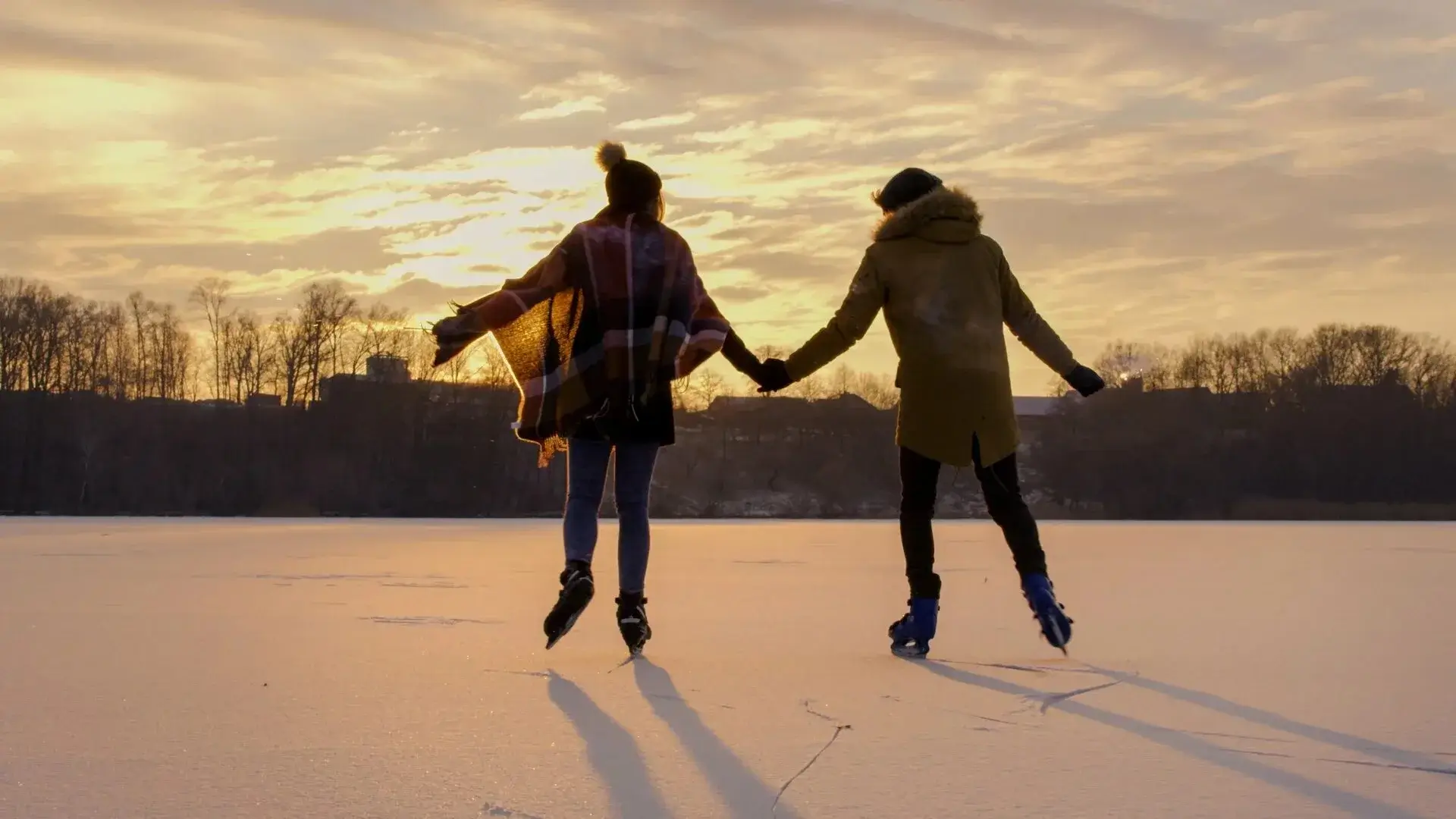 Group of friends ice skating at sunset