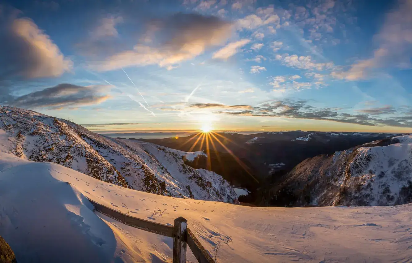 A vast, snowy mountain landscape at sunrise.
